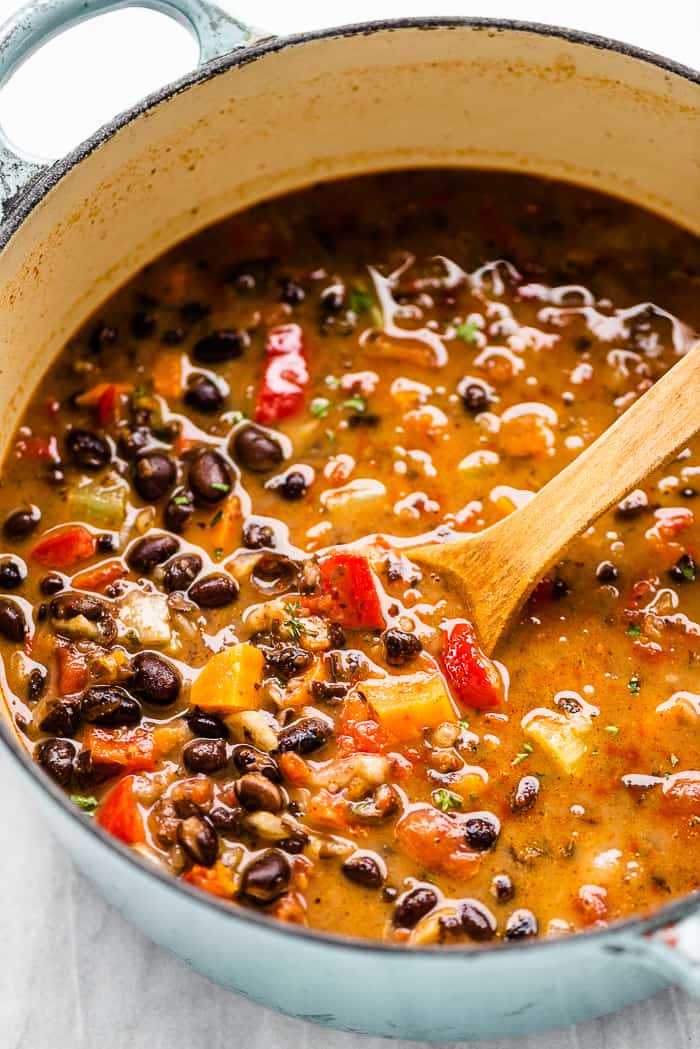 Black bean soup is easy to make, delicious, and healthy. It's made with kitchen-staples like cans of black beans, carrots, onions, and spices so you can make this recipe anytime you're craving Tex-Mex flavors. A closeup of a pot of bean soup.