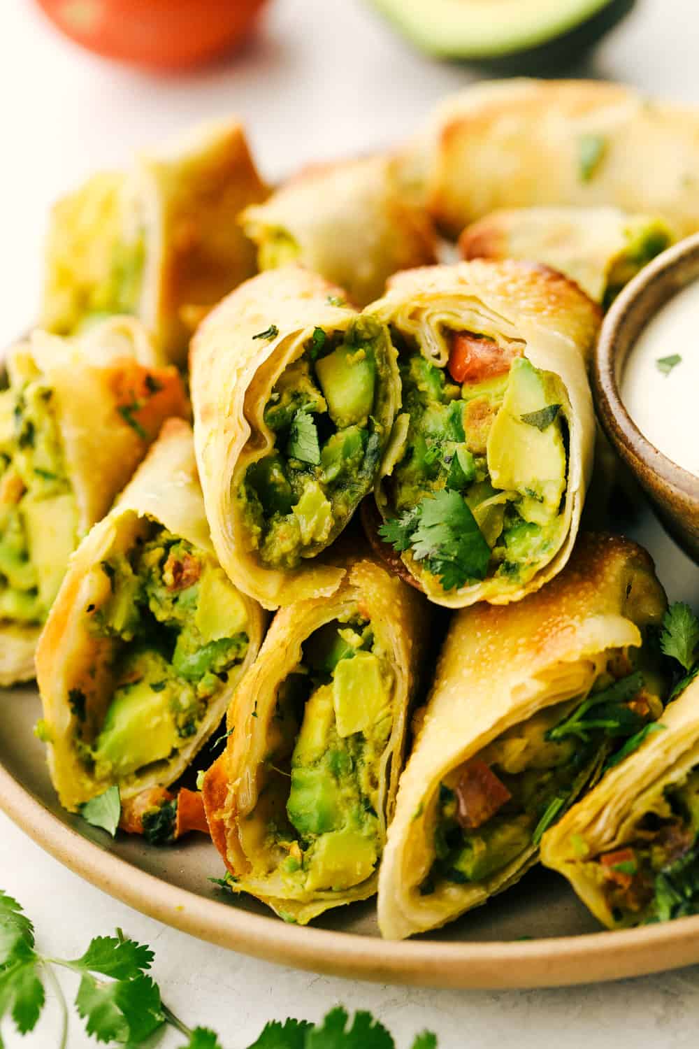 Whether it is for a party or for your own private dinner, Avocado Egg Rolls in an air fryer are the appetizers to make. Crispy and golden on the outside, creamy and decadent on the inside. You have to try these! Avocado egg rolls split and layered on a plate.