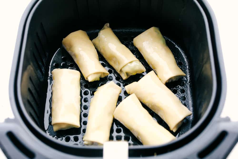 Whether it is for a party or for your own private dinner, Avocado Egg Rolls in an air fryer are the appetizers to make. Crispy and golden on the outside, creamy and decadent on the inside. You have to try these! Air fryer basket filled with avocado egg rolls for frying.