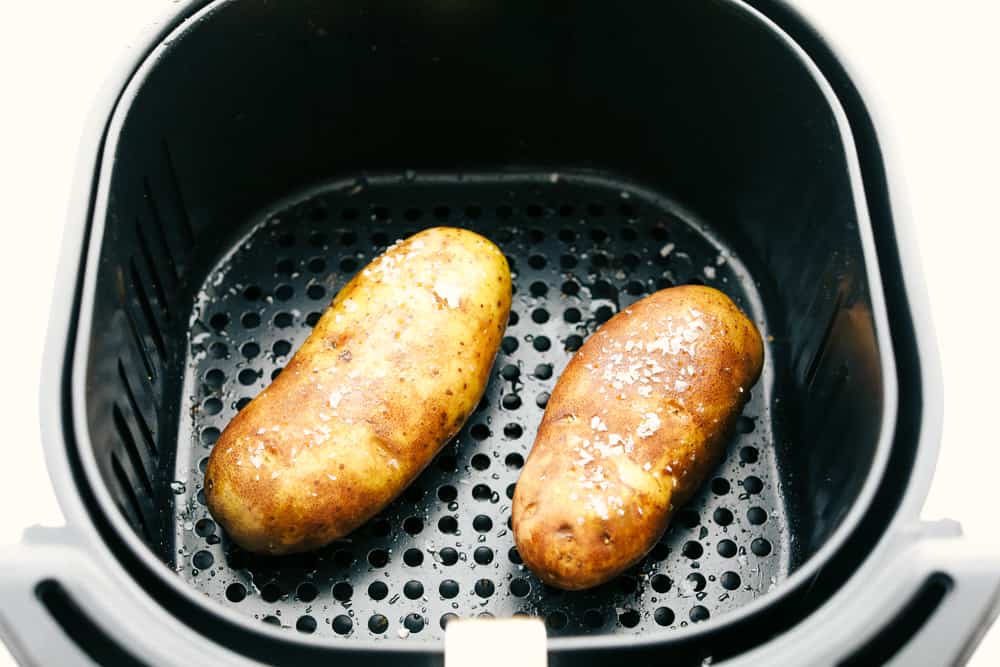 Perfect Air Fryer Baked Potatoes are crispy on the outside and tender fluffy on the inside. Perfect addition to any meal, or a meal all on it's own! Potatoes in the air fryer sprinkled with kosher salt.