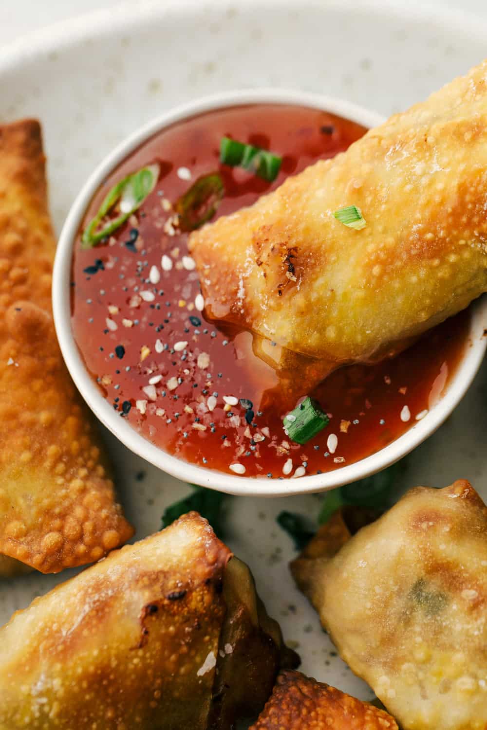 Egg Roll lovers, this Crispy Air Fryer Egg Roll Recipe is for you! Crispy, crunchy outside, tender filling inside, without the extra fat of frying or drying out from oven cooking. These are what you have been waiting for! Egg rolls on a plate and one being dipped in sauce.
