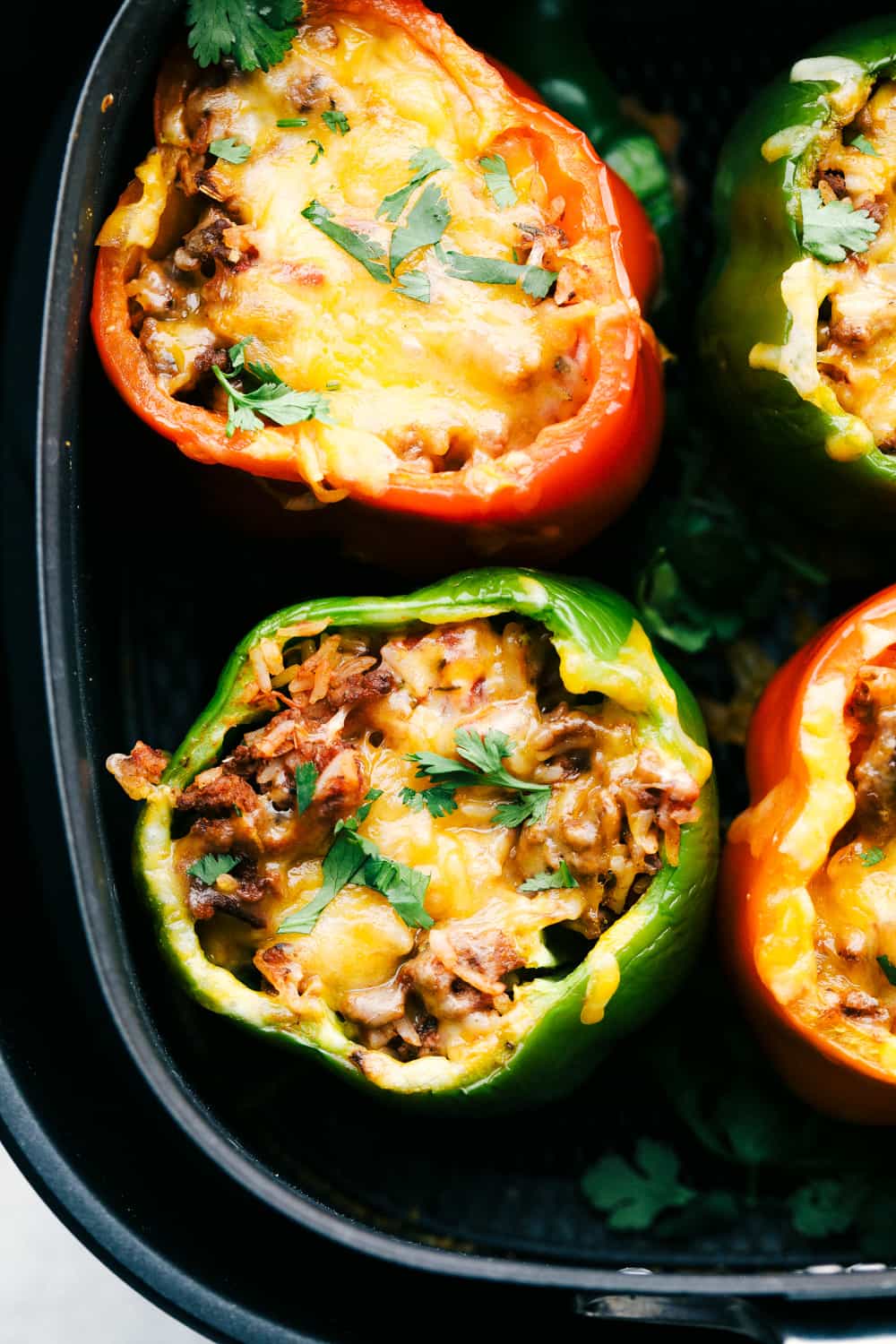 A super easy and delicious dinner begins here with Air Fryer Stuffed Peppers. Filled with a savory mixture and cooked to tender perfection, it is going to be a family favorite! Air Fryer Stuffed peppers with cheesy rice filling.
