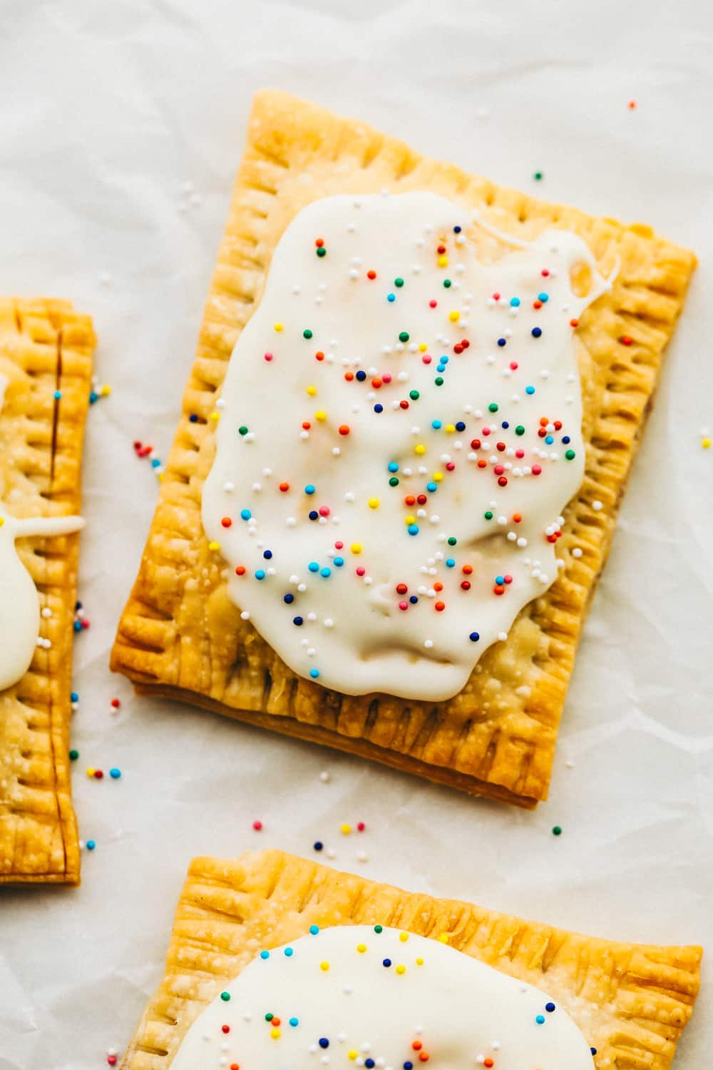 Make your kids excited to get out of bed with these Homemade Air Fryer Pop Tarts! These pop tarts have a crisp flakey crust with a tender sweet filling, and topped with frosting, of course! Strawberry homemade pop tart with frosting and sprinkles.