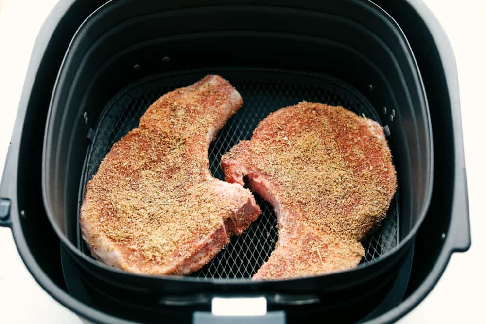 Air Fryer Pork Chops are the best pork chops ever! With a golden seasoned crust and fork tender juicy insides, it is makes these the perfect pork chops. Seasoned pork chops in the air fryer basket.