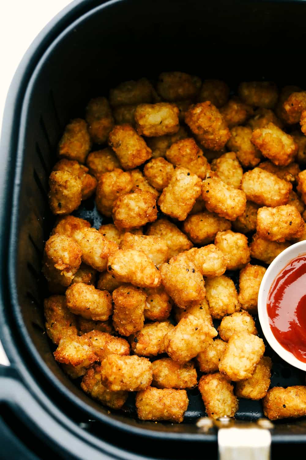 Air Fryer Tater Tots are just about the greatest thing to happen to potatoes ever! Crispy golden on the outside and tender on the inside, these are insanely delicious! Golden and crispy tater tots in the air fryer with a side of ketchup.
