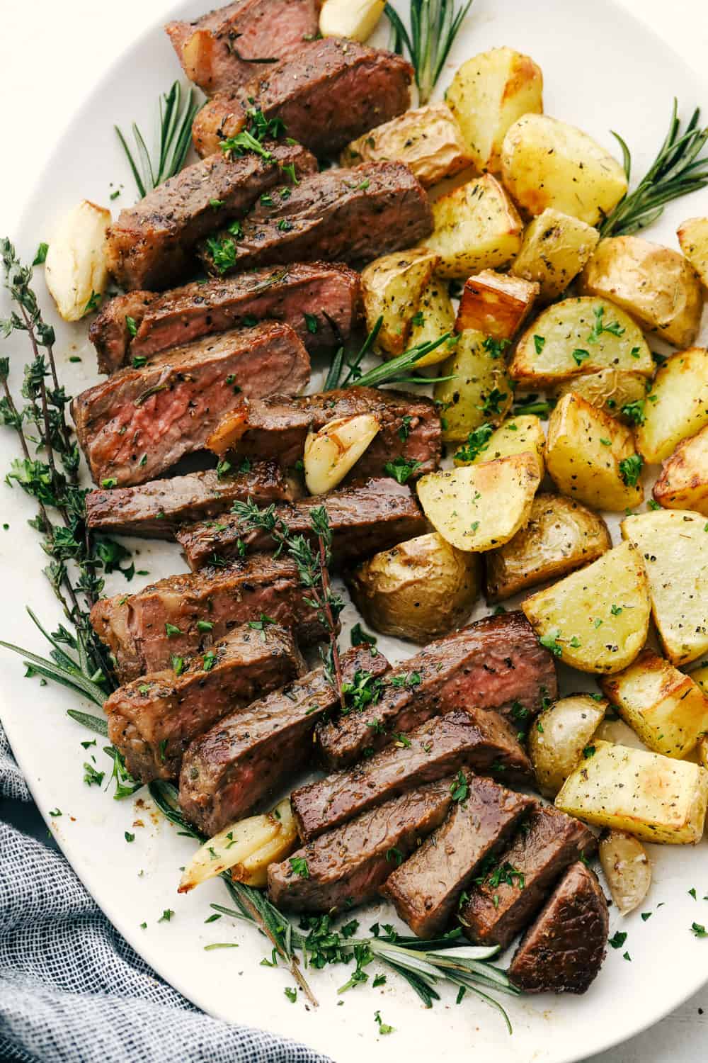 Skillet seared New York Steak is one of the best steaks you'll ever have!ย It's tender, juicy and full of flavor! Cut up steak and potatoes on a white plate.