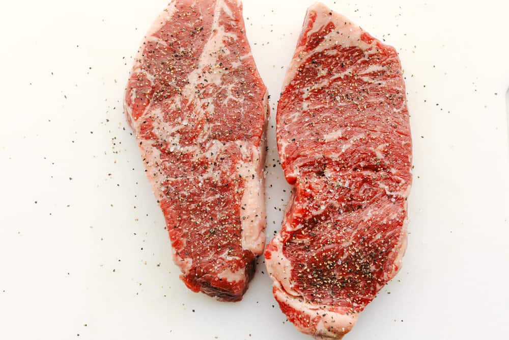 Skillet seared New York Steak is one of the best steaks you'll ever have!ย It's tender, juicy and full of flavor! Two steaks seasoned with salt and pepper.