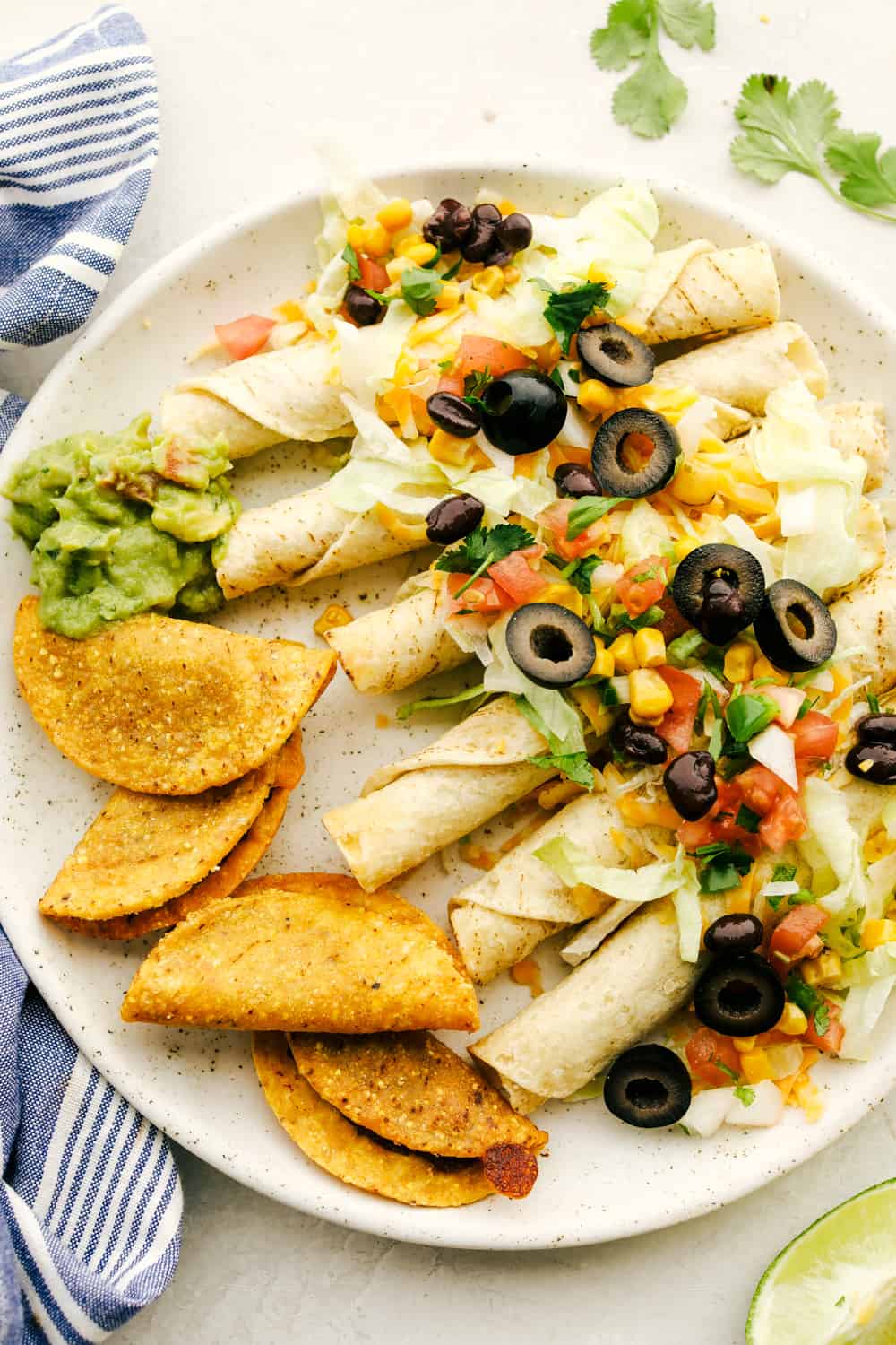 This taco board is everything you need to have for the ultimate get together! It is the perfect combination! Taquitos smothered with cheese, olives, corn and tomatoes with tacos and guacamole on the side.