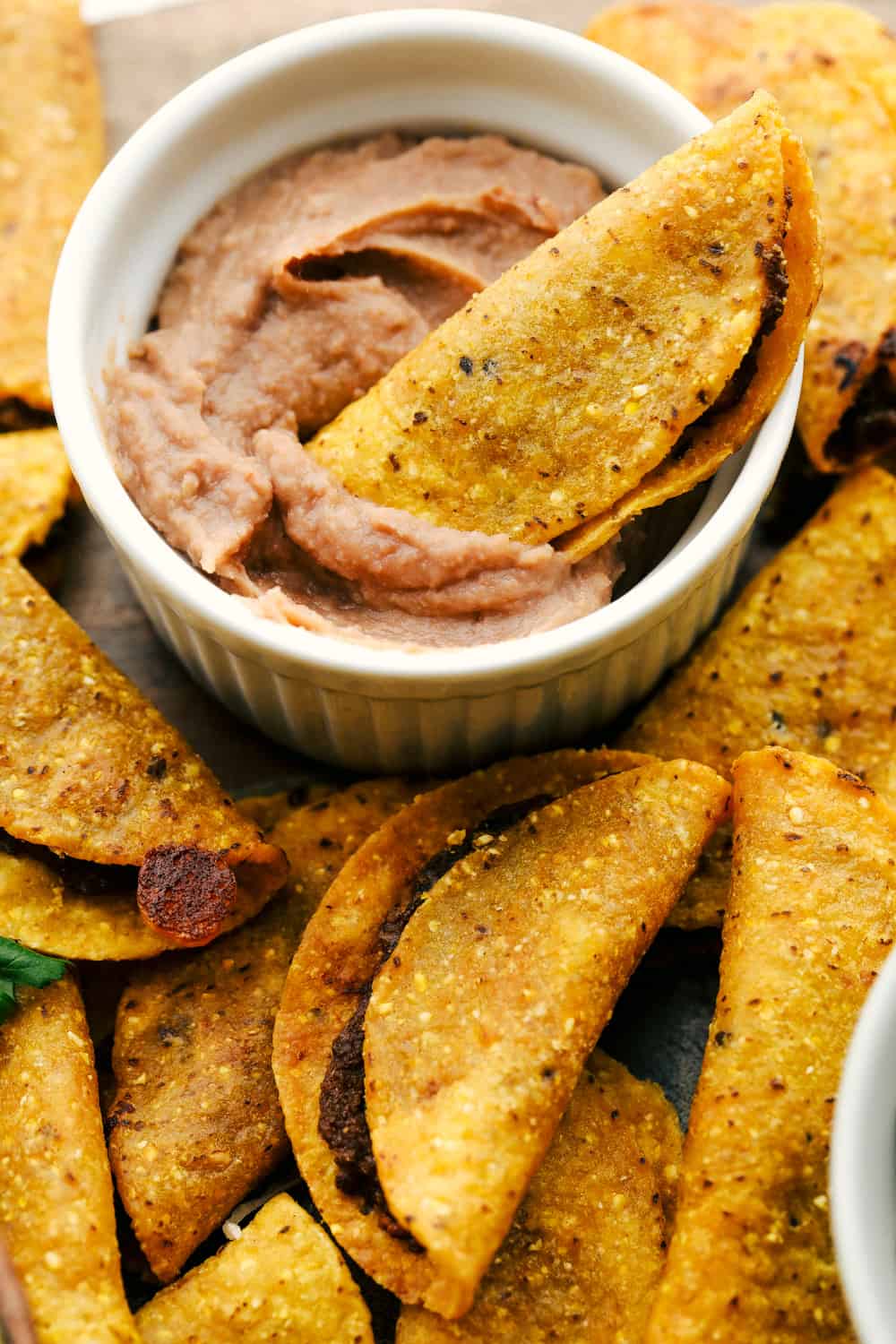 This taco board is everything you need to have for the ultimate get together! It is the perfect combination! A taco being dipped in the bean dip.