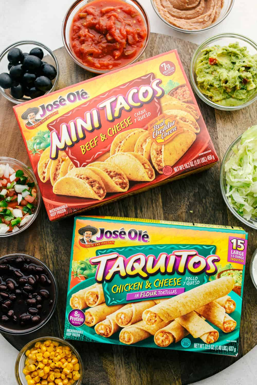 This taco board is everything you need to have for the ultimate get together! It is the perfect combination! Mini tacos and taquitos in a box with bowls of dips and vegetables.