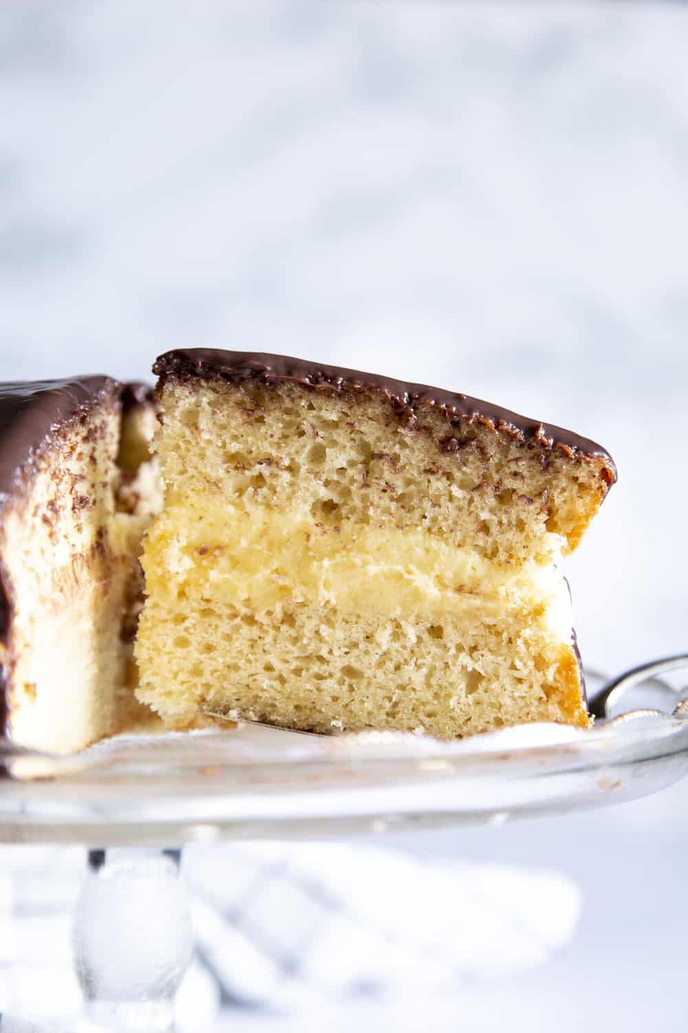 Boston Cream Cake is an American classic sure to win you over. It's a decadent light, fluffy cake, filled with a vanilla custard and topped with a rich chocolate ganache. A side view of the layers in the Boston Cream Cake.