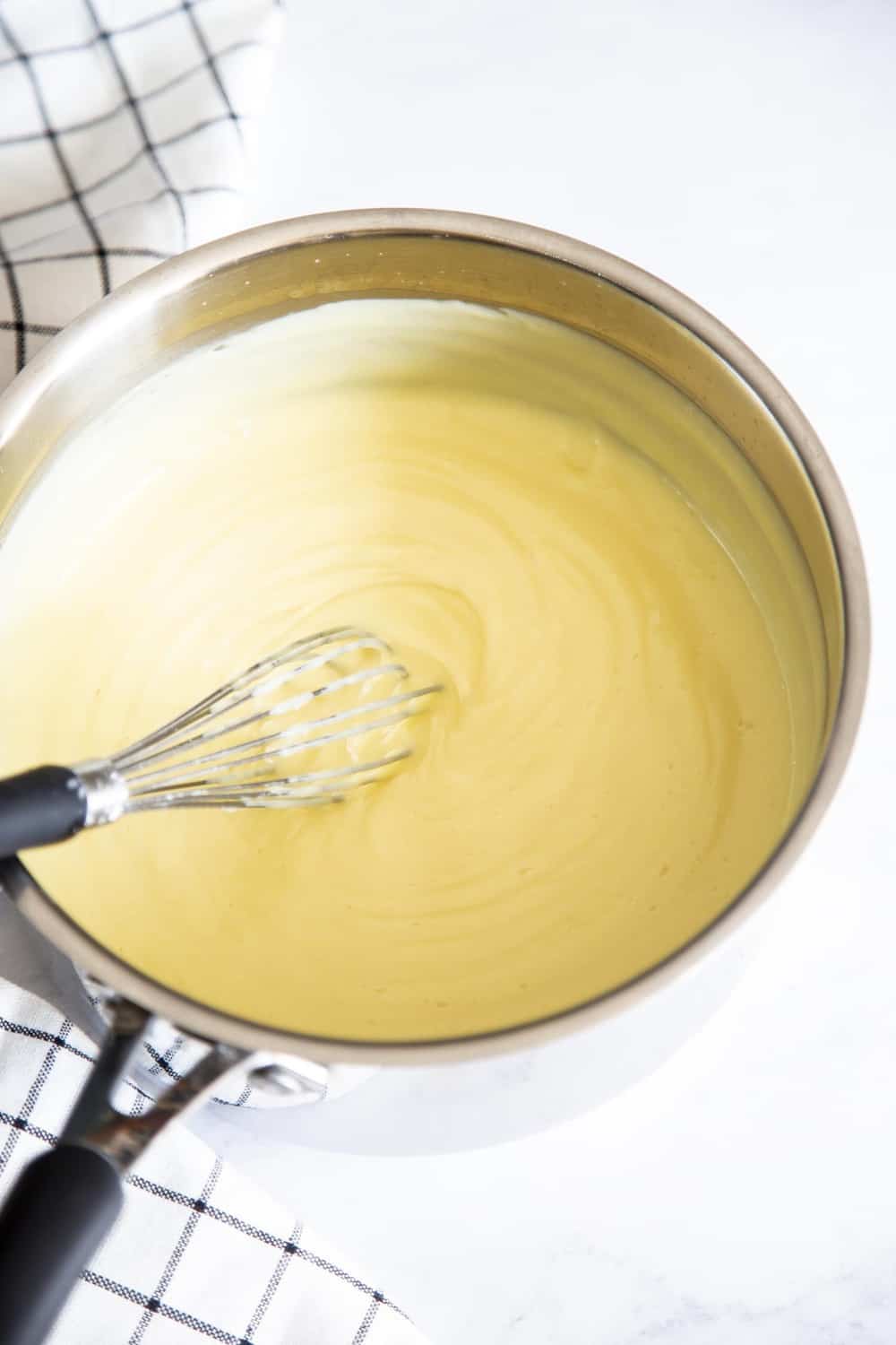 Boston Cream Cake is an American classic sure to win you over. It's a decadent light, fluffy cake, filled with a vanilla custard and topped with a rich chocolate ganache. Saucepan full of cream filling for the boston cake.