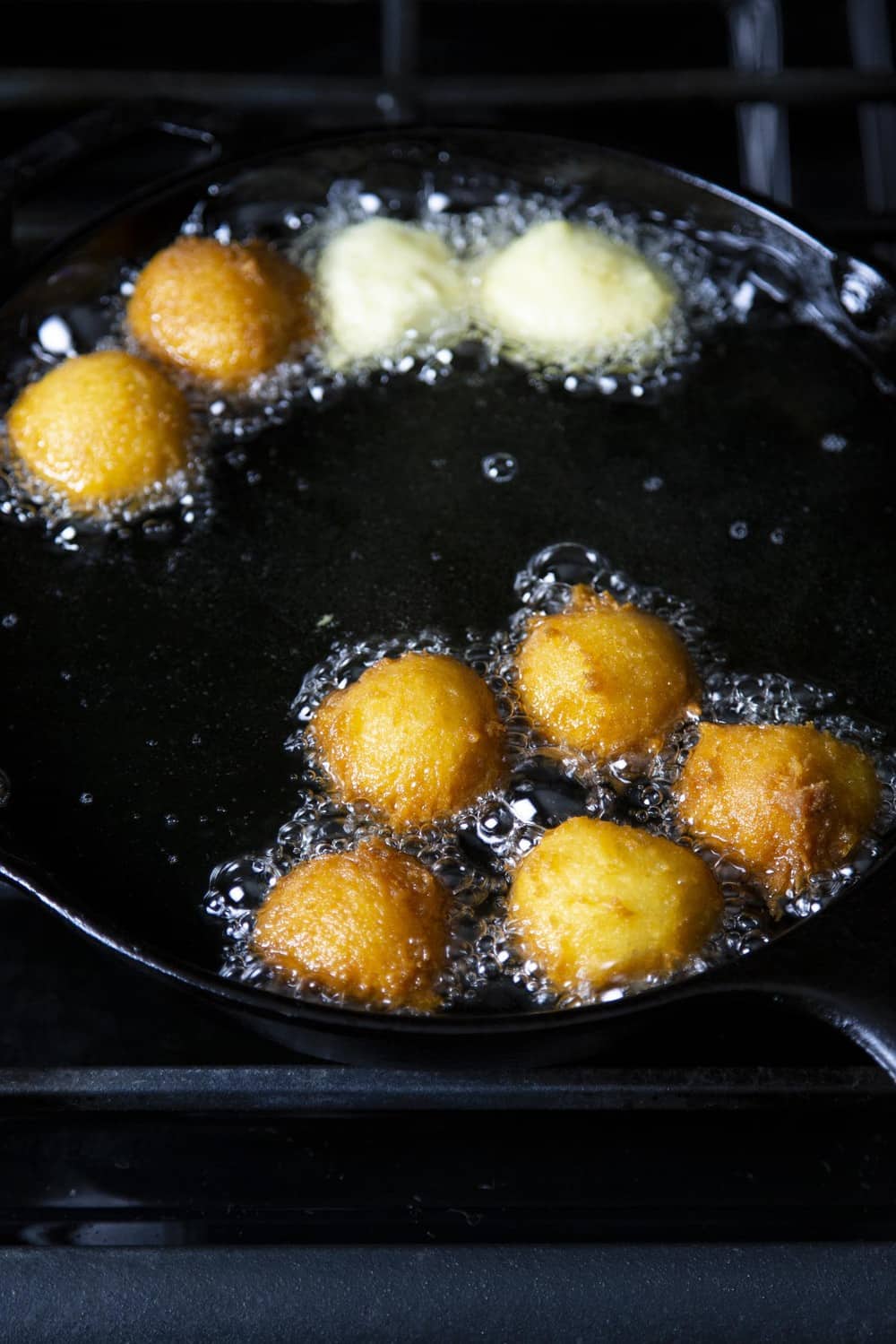 Donut Holes have to be the best part of making donuts. They are bite size and fun to eat! Donut holes frying in a pan of oil.