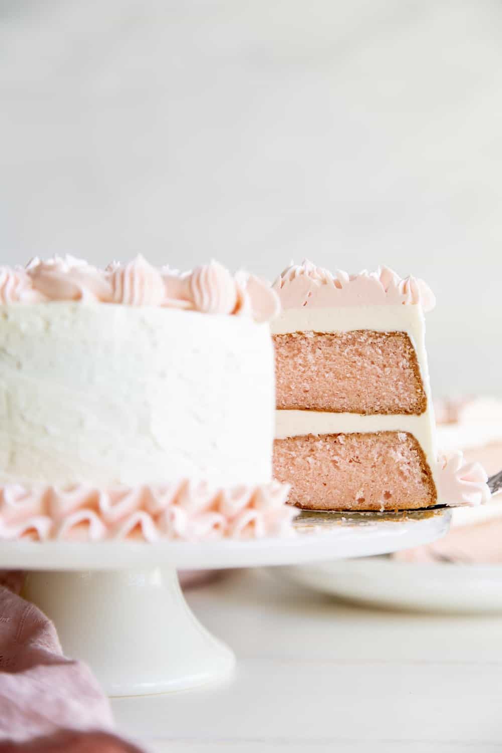 This rich decadent Pink Velvet Cake is going to be a quick favorite.It's absolutely perfect for Valentine's Day, baby showers or any other special occasions. The inside of the pink velvet cake with white frosting and pink frosting flowers.