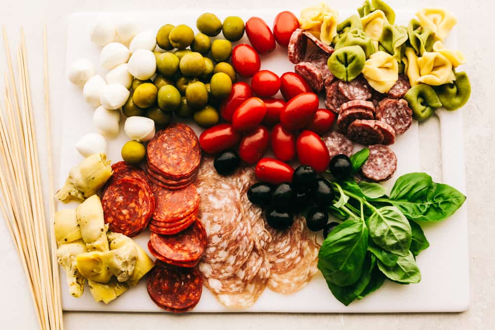 Antipasto Skewers are a super easy and delicious appetizer, perfect for any occasion. Colorful and full of flavor, these are true crowd pleaser! Ingredients for antipasto skewers on a cutting board ready to be assembled.