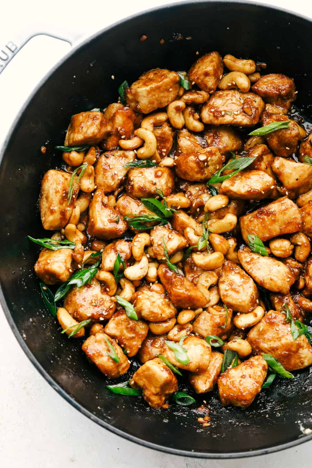 Cashew chicken in a wok with garnish.