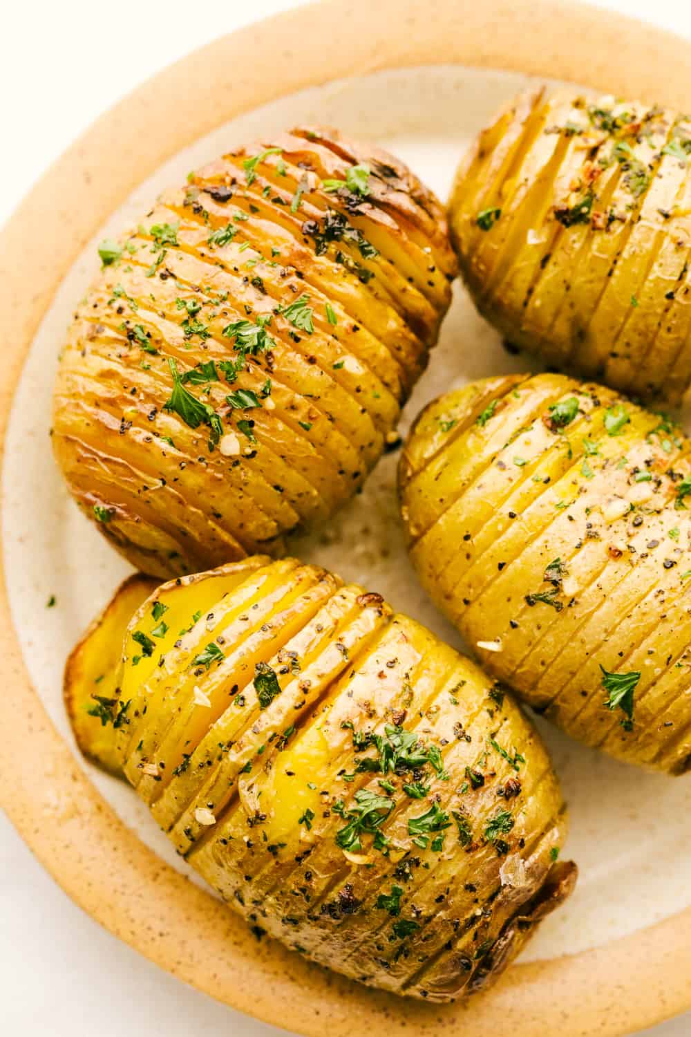 Air Fryer Garlic Butter Hasselback Potatoes are going to be your new favorite side dish. They are fried to a golden brown and the flavor is amazing! Crispy air fryer hasselback potatoes on a plate.