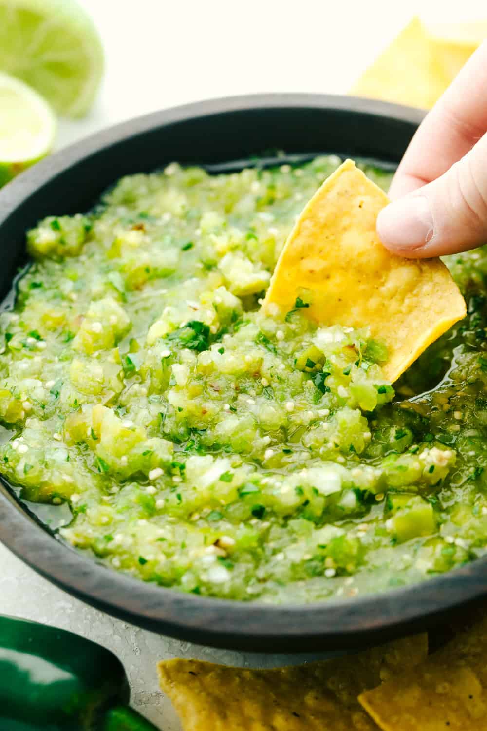 Salsa Verde is fresh, spicy and way better than anything you will find in a jar. Super easy and quick, whip it up for a party in no time! Dipping a chip in homemade salsa verde.