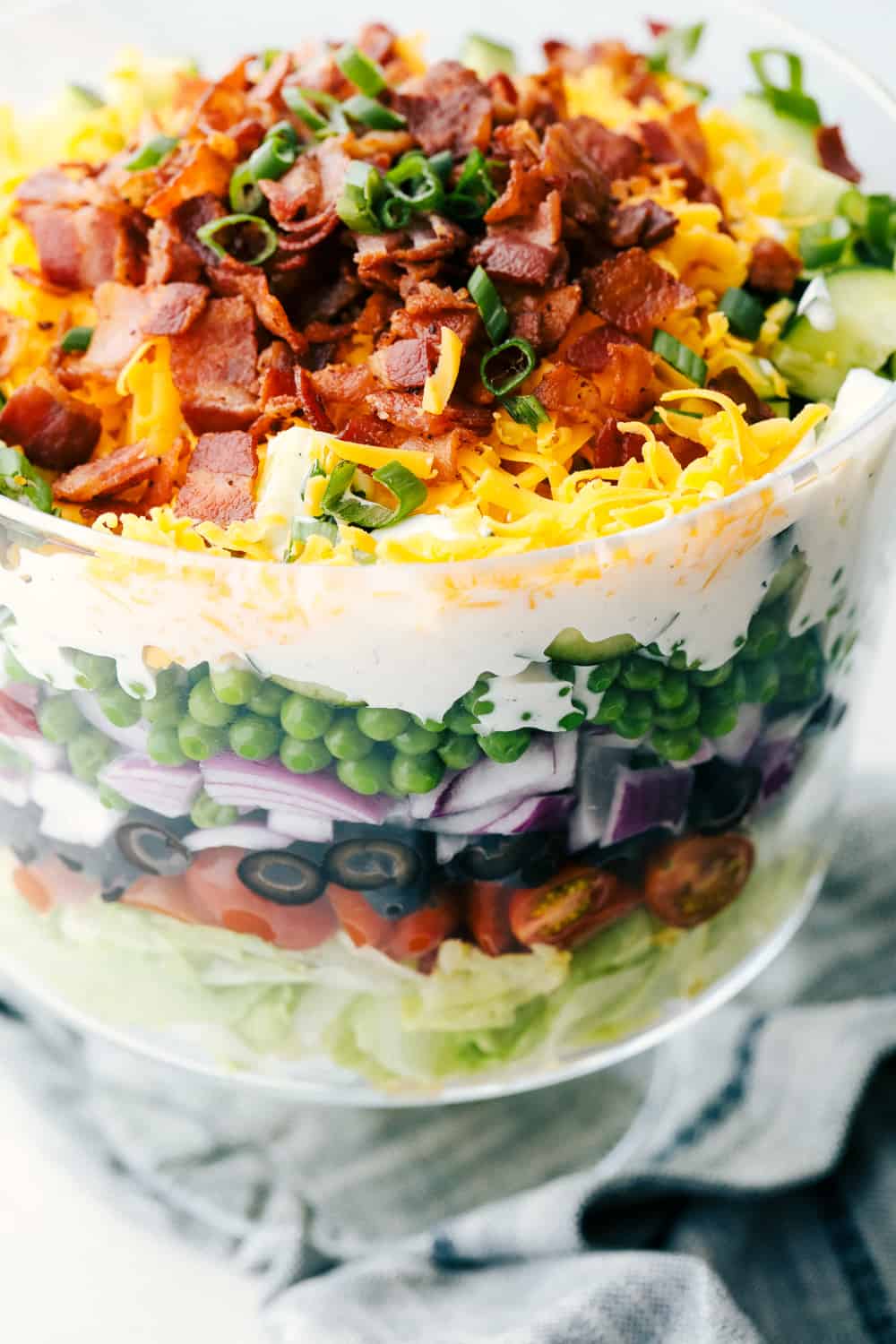 7 Layer Salad is super simple, customizable and amazingly delicious. This sensational traditional salad is a table topper as well as a scrumptious side dish. Upclose picture of the salad in a glass bowl.