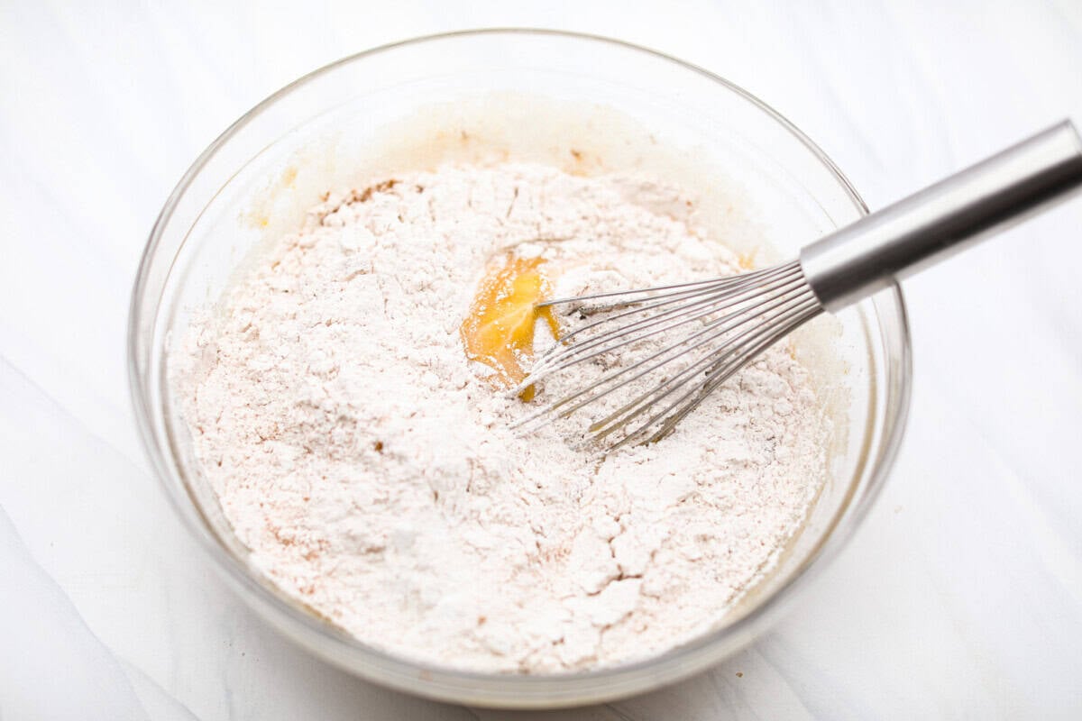 My carrot cake bars are so easy to make and unbelievably delicious. They are moist from the freshly grated carrots, perfectly spiced, and topped with an incredibly fluffy cream cheese frosting. Dry and wet ingredients in the same bowl being whisked together.