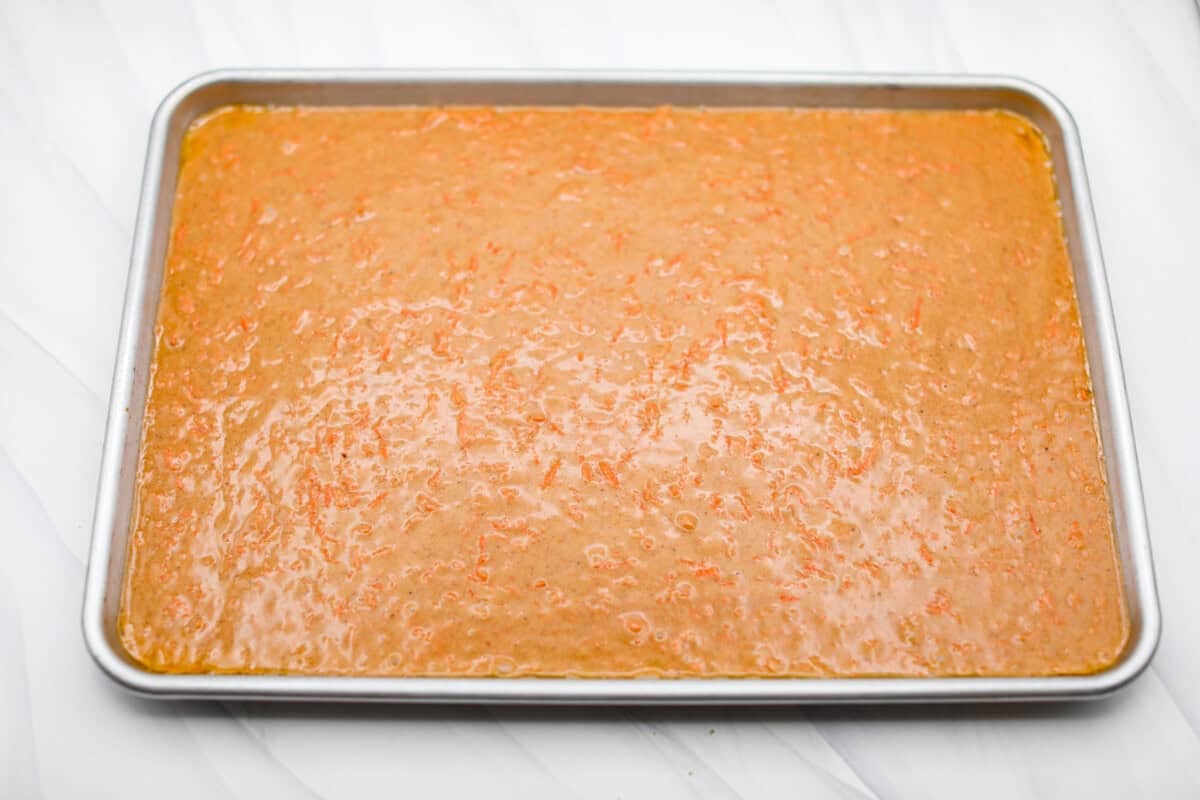 My carrot cake bars are so easy to make and unbelievably delicious. They are moist from the freshly grated carrots, perfectly spiced, and topped with an incredibly fluffy cream cheese frosting. Sheet pan with carrot cake bar batter poured in ready to be baked.
