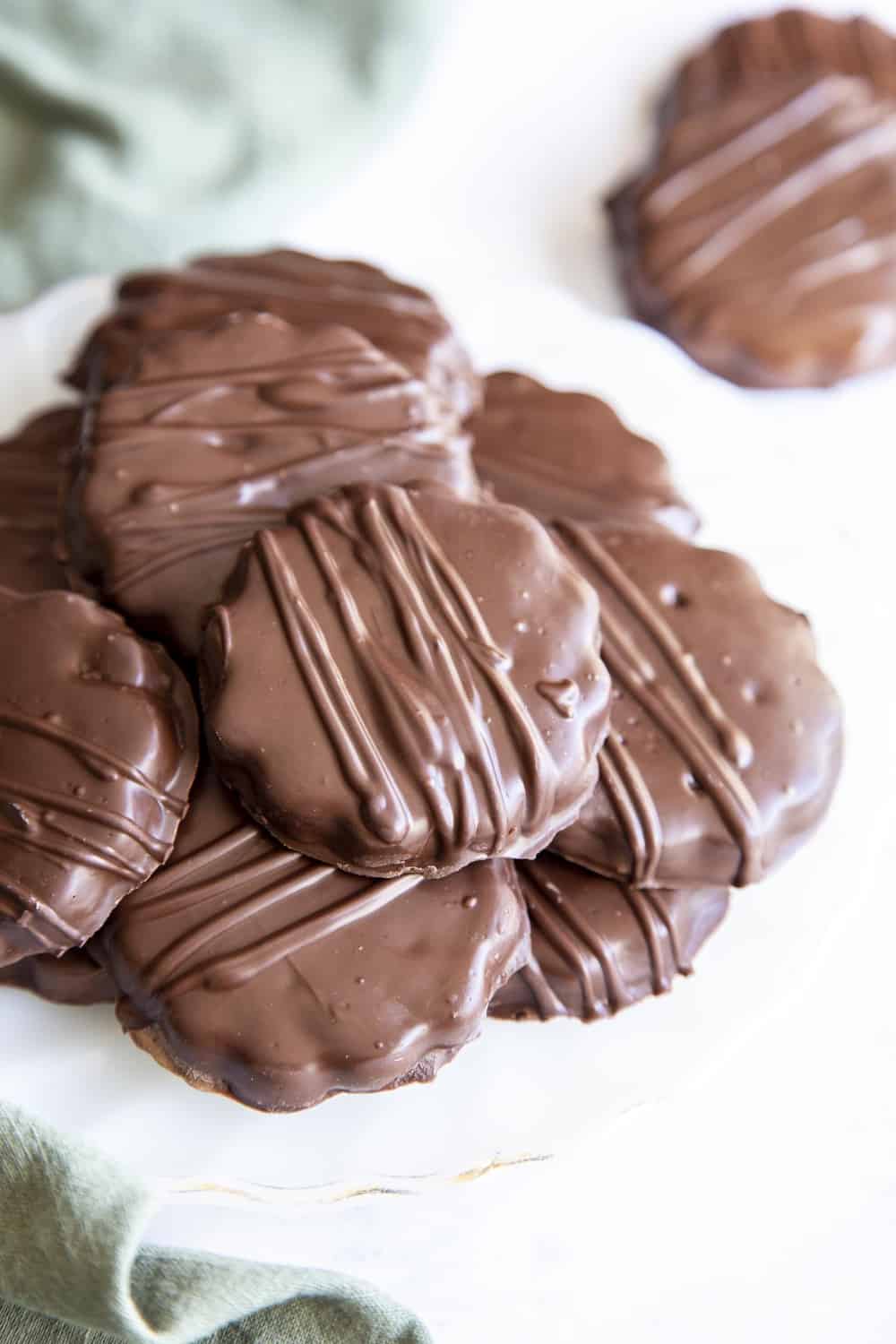 These Thin Mints are way better than the popular boxed version! Perfectly crispy chocolaty cookies are sweetened with just the right amount of mint! Crispy chocolatey homemade thin mint cookies staked on a plate.