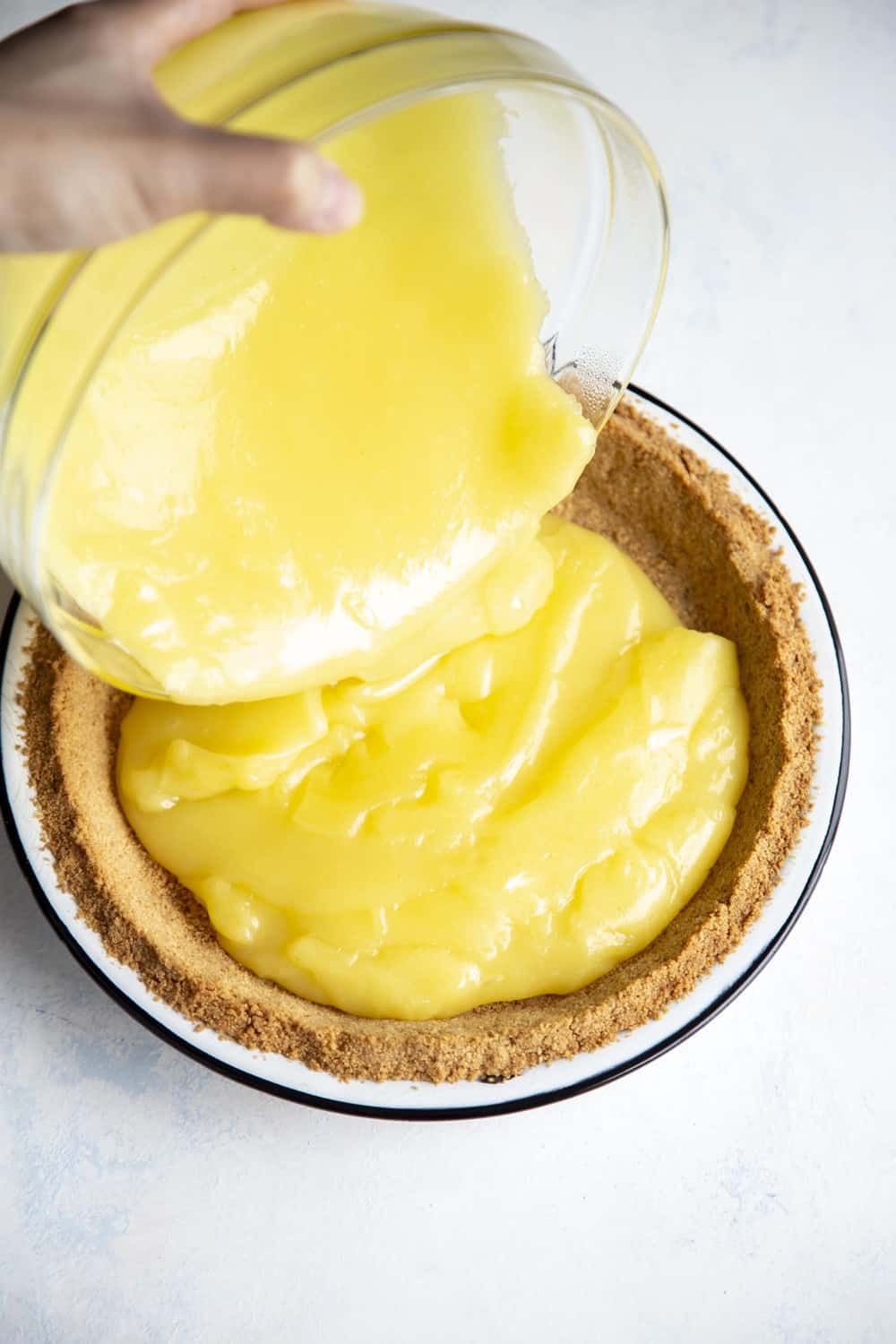 Lemon Meringue Pie is literally a slice of sunshine! Tart and tangy, bright lemon filling is topped with clouds of fluffy meringue that is going to blow your taste buds. Pouring the lemon filling in the pie crust.