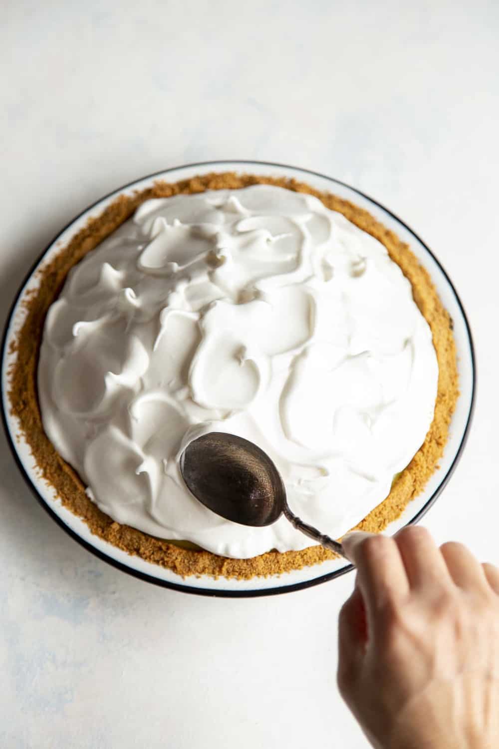 Lemon Meringue Pie is literally a slice of sunshine! Tart and tangy, bright lemon filling is topped with clouds of fluffy meringue that is going to blow your taste buds. Making designs with a spoon in the meringue.