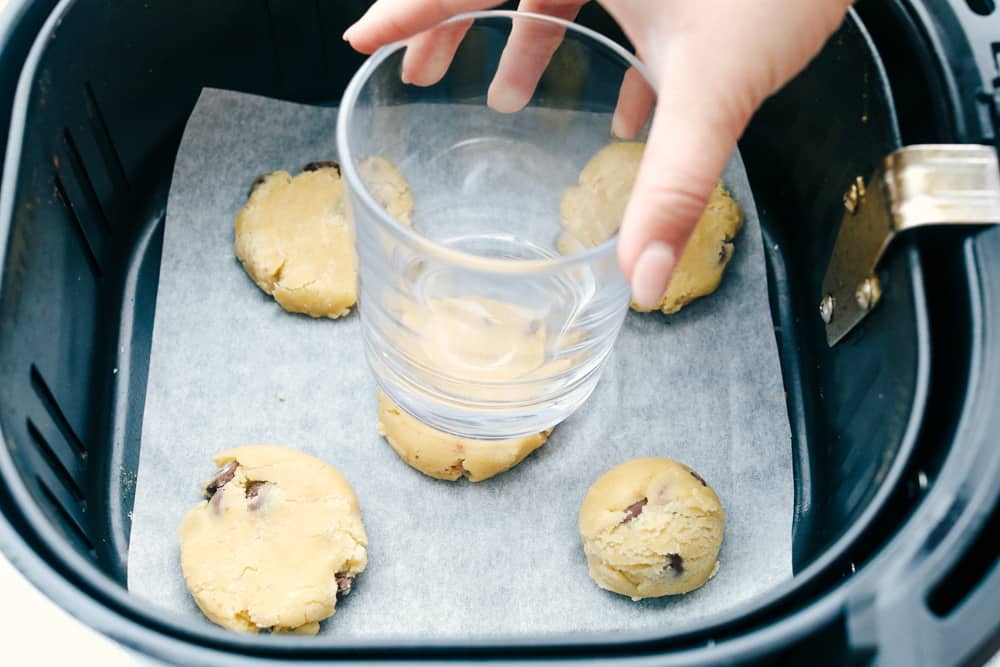 Air Fryer Chocolate Chip Cookies are crispy on the outside, ooey gooey on the inside. These cookies are going to change the way you cookie! Flattening the cookies in the air fryer with a glass.