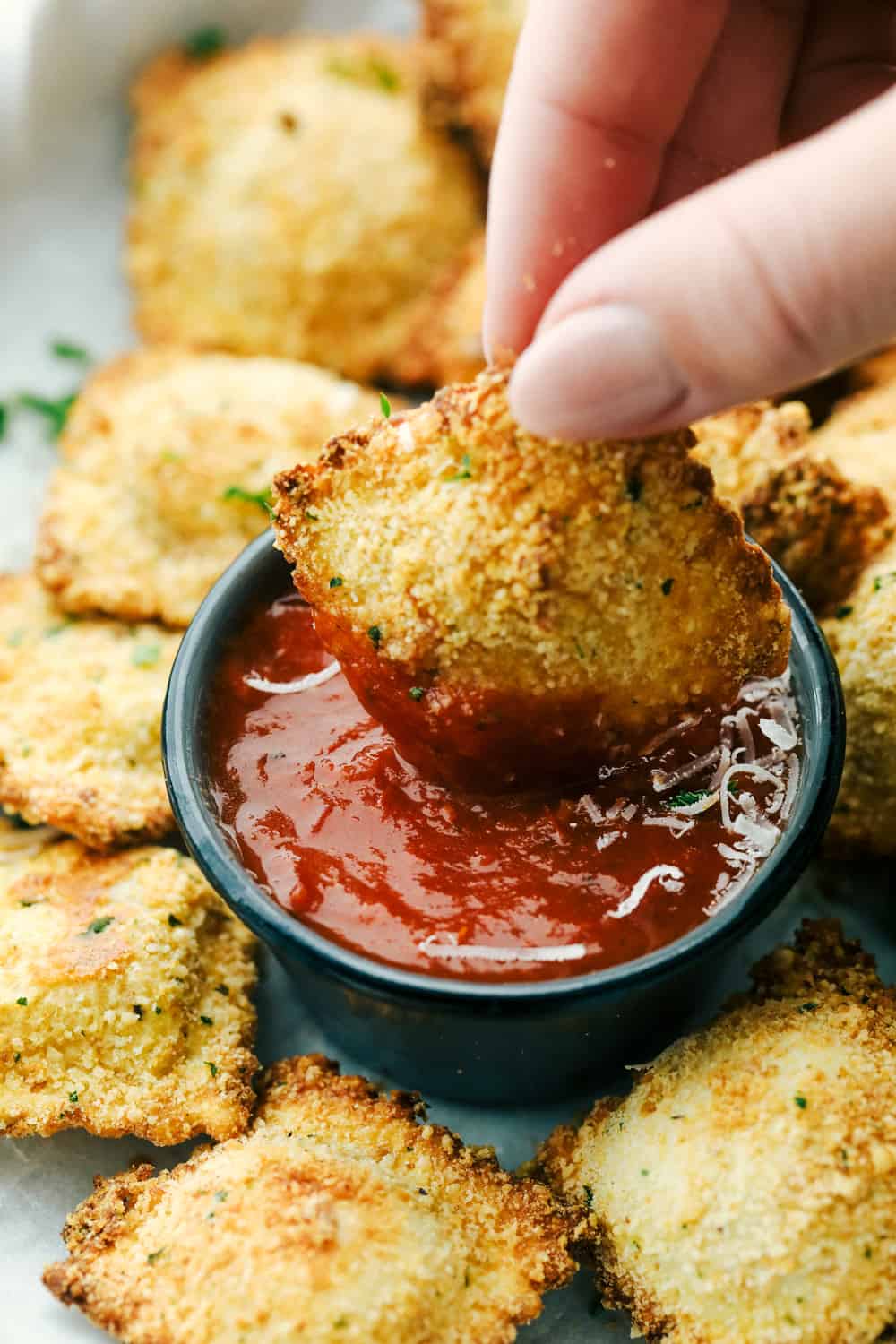 Air Fryer Toasted Ravioli are crispy golden nuggets of YUM!ย Perfect as an appetizer or even a meal, you are going to love these! Dipping toasted ravioli in marinara.