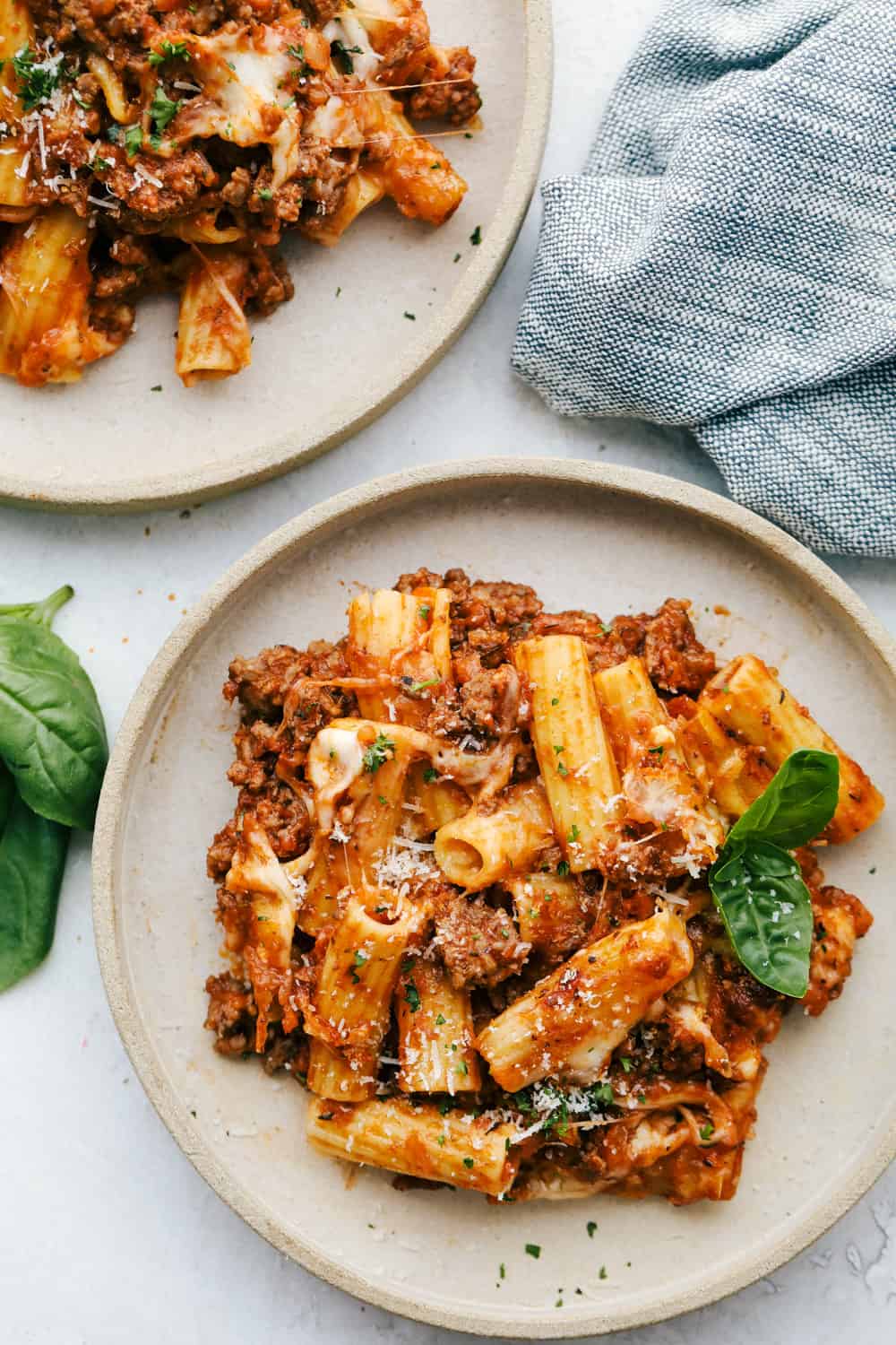 Baked Rigatoni is full of zesty meat, tender noodles and lots of cheese!ย Super simple this is the ultimate comfort food! Two plates with baked rigatoni.