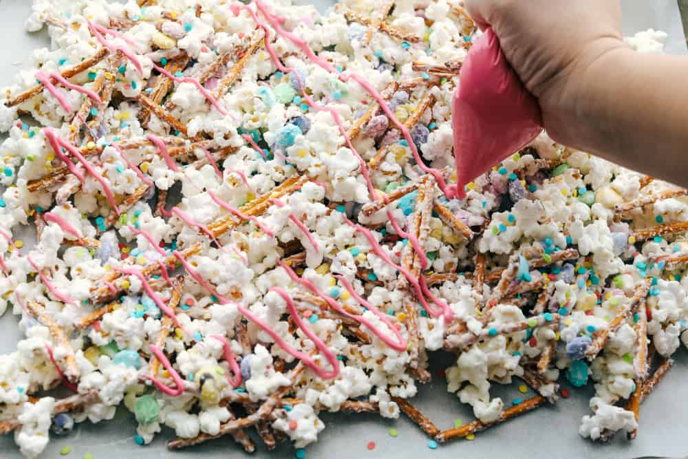 Funfetti Popcorn or Bunny Bait is a fun springtime treat that is sure to satisfy! This is a sweet salty colorful treat perfect for Easter or any other special occasion! Adding colorful candy melt drizzles to the cooking popcorn mixture.