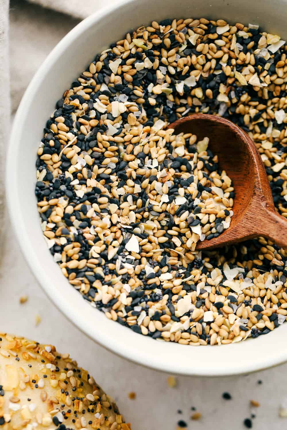 Everything Bagel Seasoning made at home takes 6 ingredients and less than 5 minutes! You are going to love this super easy and fast divine seasoning. Scooping the seasoning out of a white bowl.