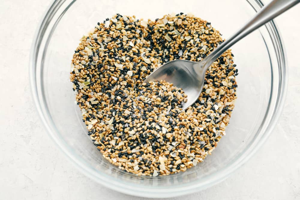 Everything Bagel Seasoning made at home takes 6 ingredients and less than 5 minutes! You are going to love this super easy and fast divine seasoning. A bowl with the everything but the bagel seasoning and a spoon.