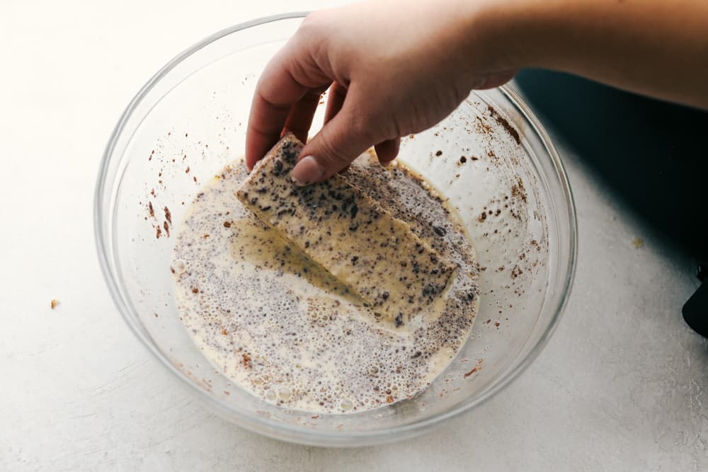 Air Fryer French Toast Sticks are a super fun fast way to make breakfast in the morning. Coated in a vanilla and cinnamon egg mixture, these fry up absolutely amazing! Dipping french toast sticks in egg mixture.