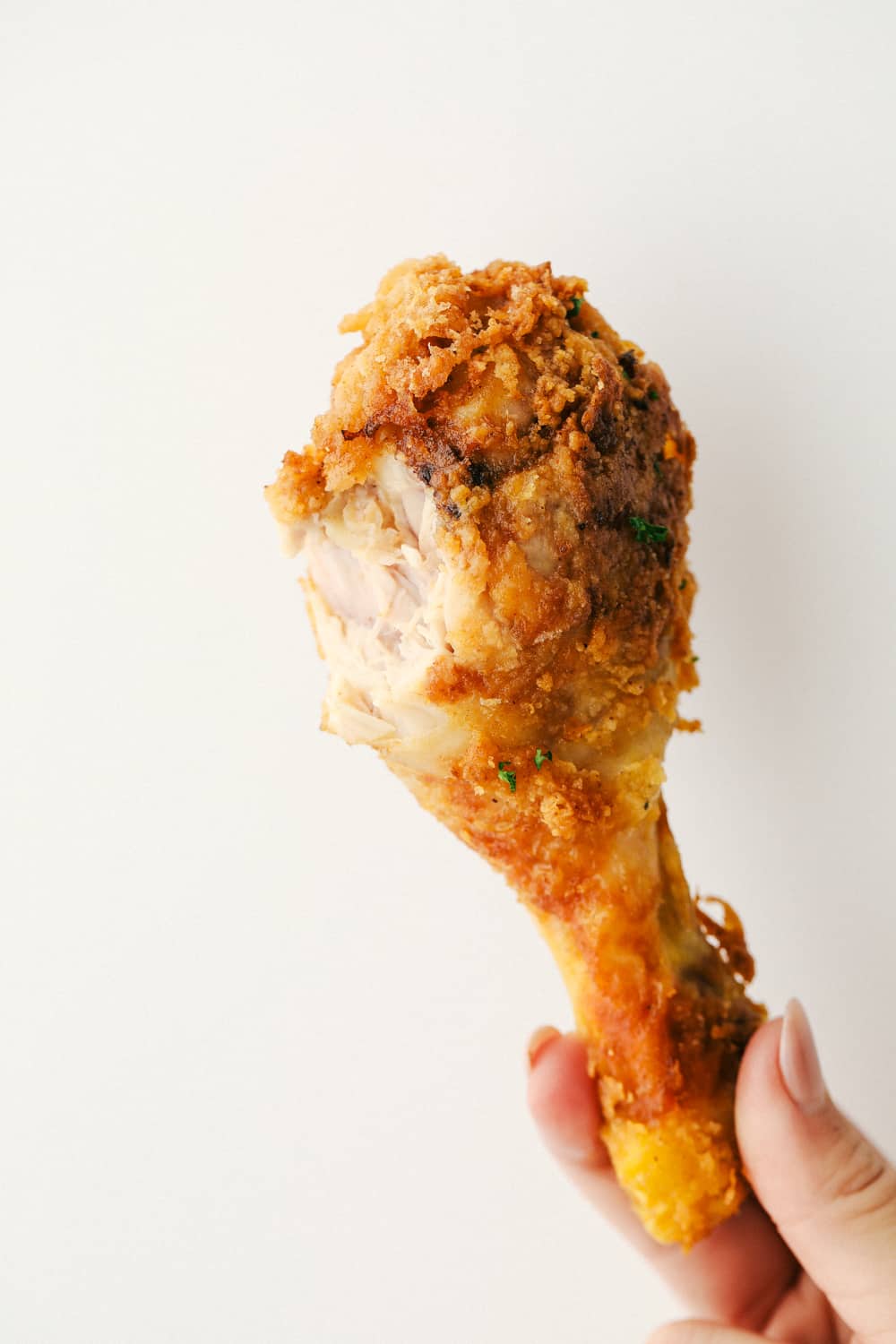 The Best Fried Chicken is literally at your fingertips! Way easier than you think and this fried chicken tastes even better than famous Roscoe's Chicken! A chicken leg with a bite taken out of it.