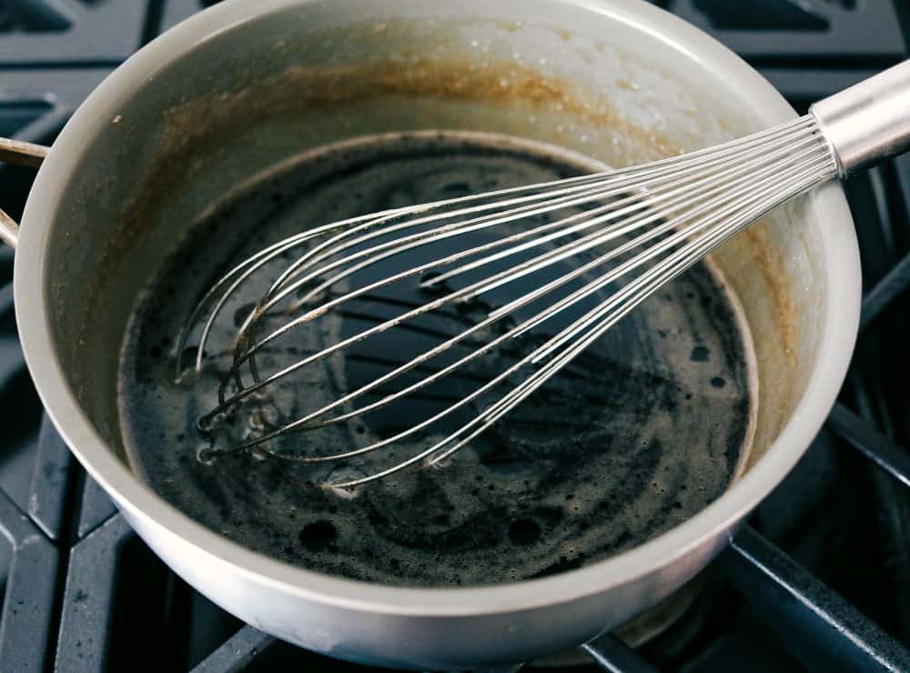 Homemade Maple Syrup is super easy and way better than store bought! Making your own syrup is going to change the way you do breakfast! Whisking a saucepan full of maple syrup.