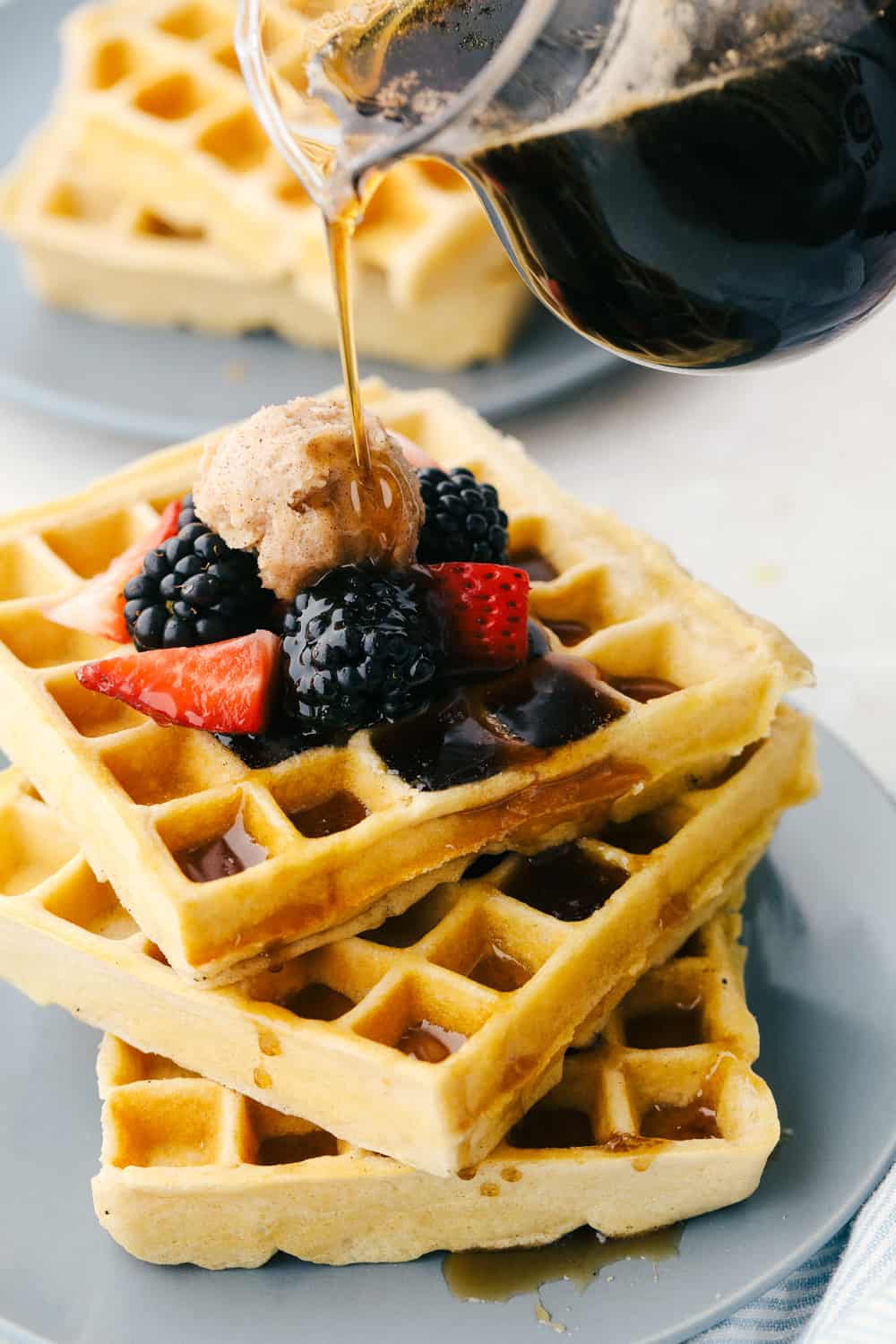 Homemade Waffles are worth waking up for! These delicate, crisp, yet fluffy waffles will melt in your mouth! Drizzling syrup on top of a stack of homemade waffles.
