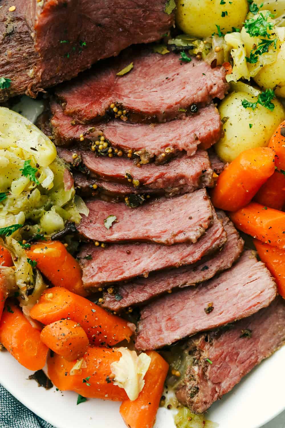 Instant Pot Corned Beef and Cabbage will make your St. Patrick's Day a breeze. The beef is tender and the cabbage and potatoes is full of flavor, you will love this! Sliced corned beef, cabbage, carrots, and potatoes on a plate.