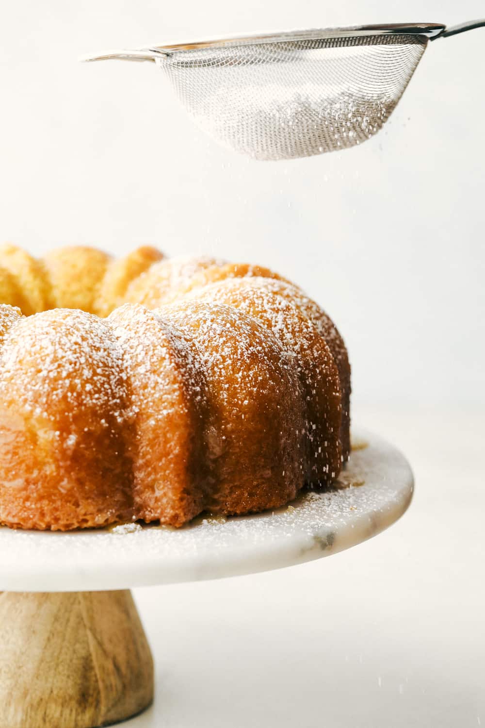 Kentucky Butter Cake is a moist, soft, buttery cake that is incredibly delicious. This luscious cake soaks up a buttery sweet sauce, that leaves a golden scrumptious crust you are going to love! Sprinkling the cake with powder sugar.