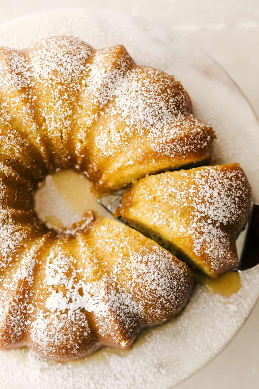Kentucky Butter Cake is a moist, soft, buttery cake that is incredibly delicious. This luscious cake soaks up a buttery sweet sauce, that leaves a golden scrumptious crust you are going to love! Cutting into the Kentucky Butter Cake.