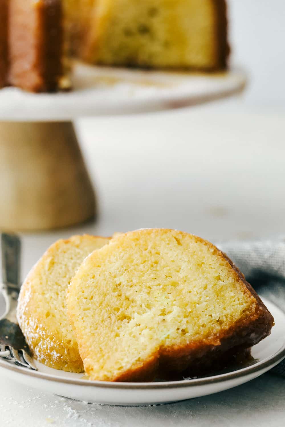 Kentucky Butter Cake is a moist, soft, buttery cake that is incredibly delicious. This luscious cake soaks up a buttery sweet sauce, that leaves a golden scrumptious crust you are going to love! Slices of cake on a plate ready to eat.