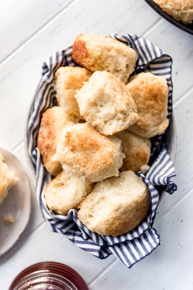 Angel Biscuits are a heavenly addition to any dinner table! These light and fluffy southern biscuits are quick and easy to throw together and they freeze great if you want to make them ahead! angel biscuits in a bowl with a striped linen napkin