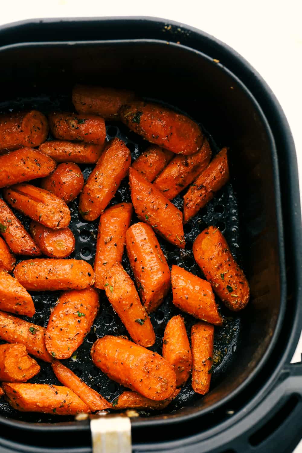 If there’s one side dish that never sticks around for long at my house, it’s these air fryer carrots! They’re crisp on the outside, tender inside, and seasoned to bring out all their natural sweetness—even the picky eaters love them! Air fryer carrots seasoned in air fryer basket.