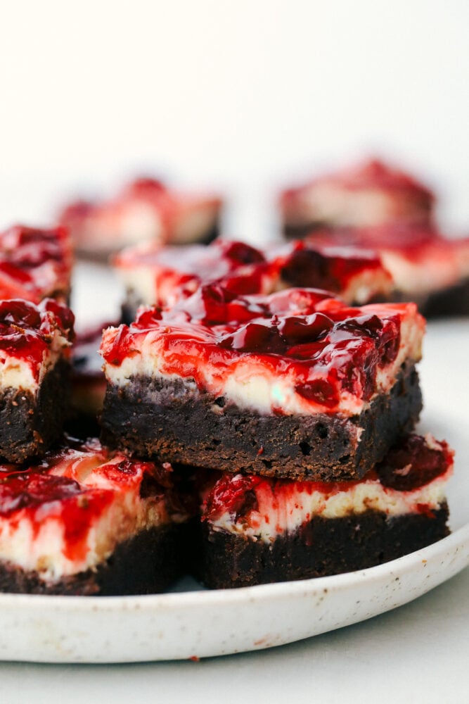 Cherry cheesecake brownies are fudgy brownies with cheesecake and premium cherry pie filling swirled on top! These brownies are rich and creamy and have three delicious desserts in one! Brownies on a plate.