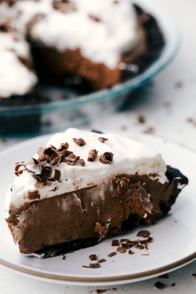 No Bake Chocolate pie is silky smooth, rich and incredibly indulgent! The perfect option when you want something exquisite, but don't want to heat up the kitchen! A slice of chocolate pie on a white plate.