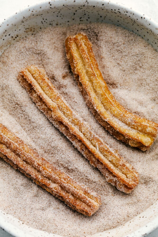 All I have to hear is the word, Churros, and my mouth starts to water. Light fluffy dough is fried and then covered in cinnamon and sugar, totally heavenly! Rolling the Churros in cinnamon and sugar.