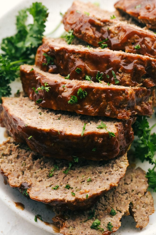Instant Pot Meatloaf is the best meatloaf I have ever had! Full of vegetables and flavor, it comes out perfectly cooked, tender and moist every time! The whole meatloaf sliced up on a plate with parsley garnish.