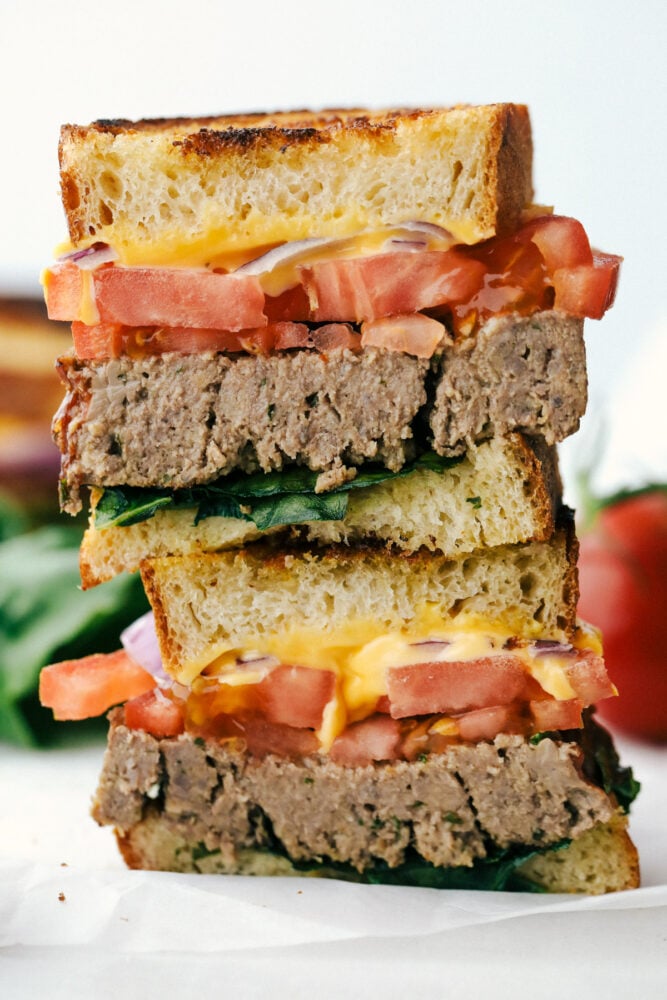 Meatloaf Sandwiches are the best combination meals with all your favorite toppings! They are juicy, full of flavor and perfect for lunch or dinner! Two halves of the grilled meatloaf sandwich stacked on top of each other.