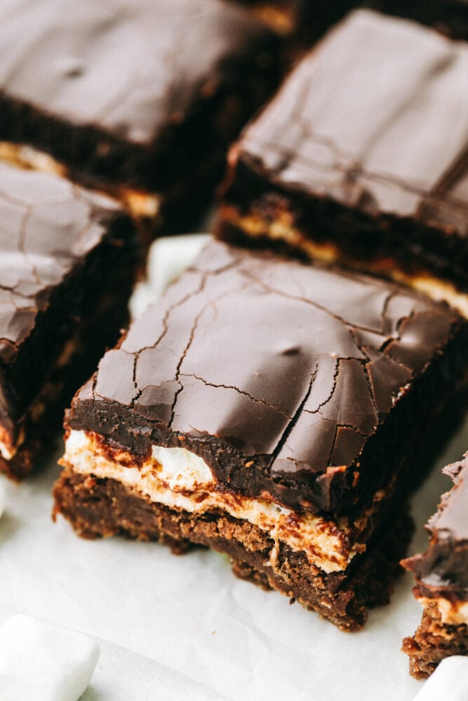 Mississippi Mudslide Bars are a chewy brownie base, topped with a fluffy marshmallow layer, and finished off with a rich and silky chocolate frosting. They are so addictive! Mississippi Mudslide Bars lined up in a row.